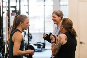 Three women talking and laughing in a strength class.