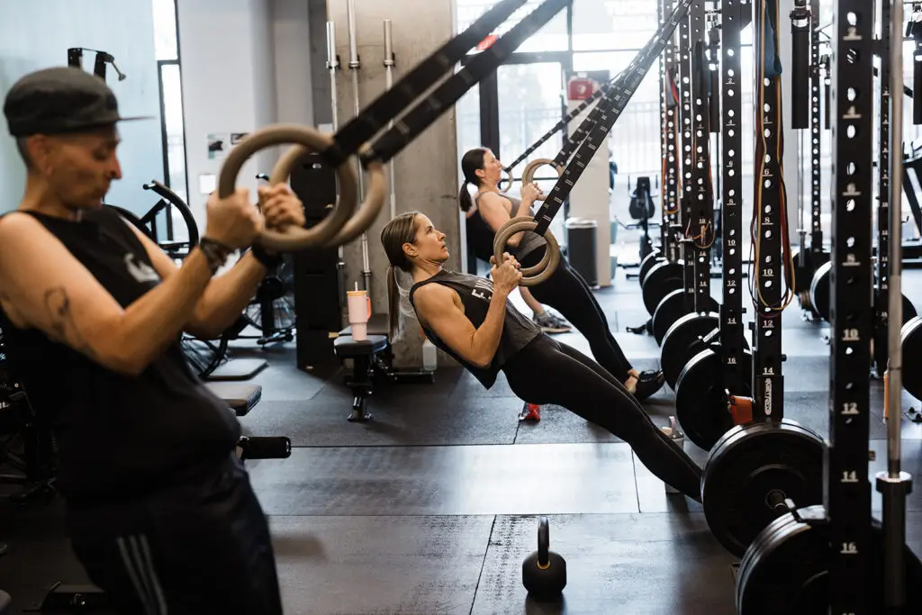 Several athletes performing a ring row exercise in a strength class