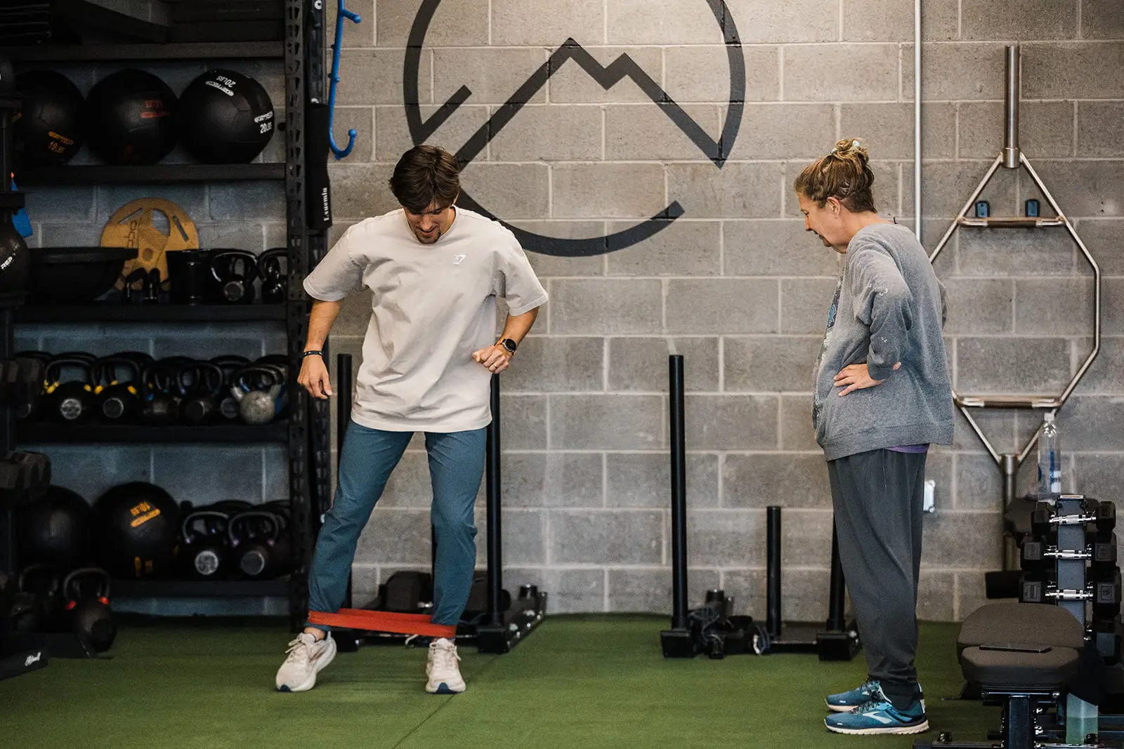 Male strength coach teaching a side step to a middle-aged female client