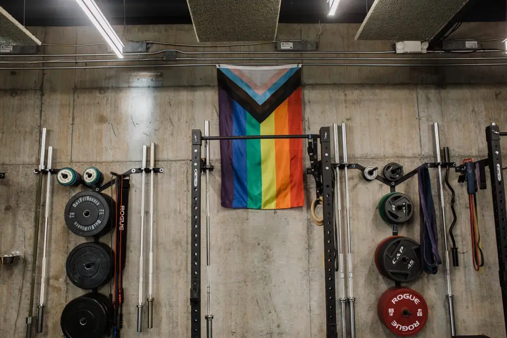 Pride flag displayed directly behind a squat rack at EVOLVE Flagstaff