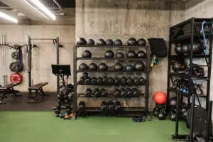 Dumbbell and medicine ball storage rack alongside a Peloton bike at EVOLVE Flagstaff