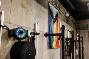 Pride flag behind a squat rack viewed from a side angle at EVOLVE Flagstaff