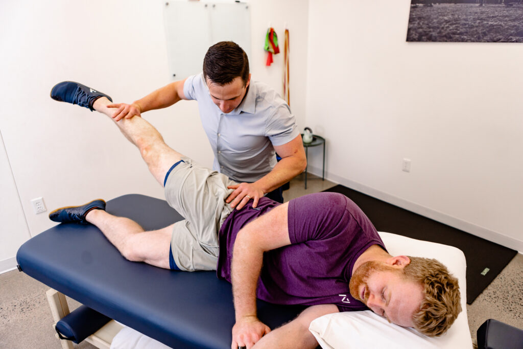Male physical therapist testing the hip strength of a male patient.
