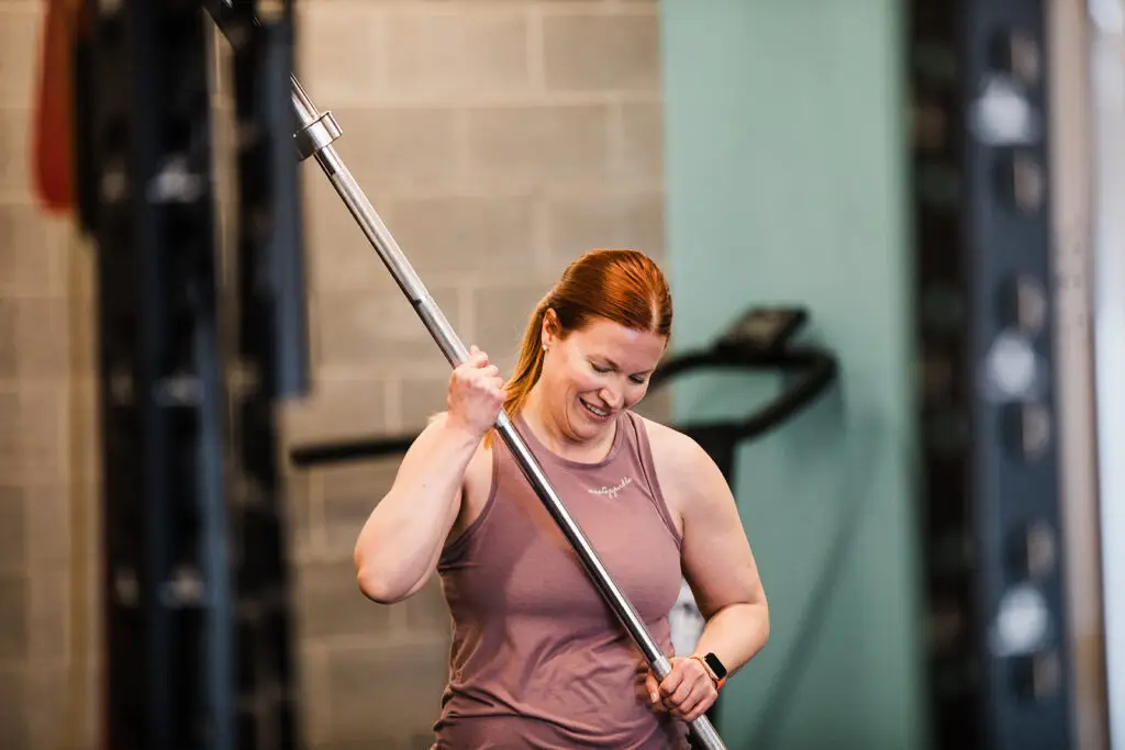 Woman smiling while putting away a barbell at EVOLVE Flagstaff
